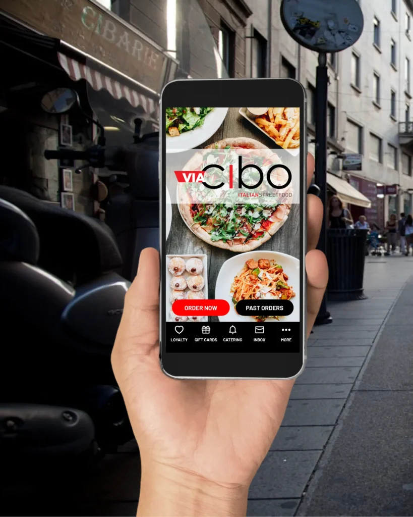 Hand holding phone showing a food-ordering app with pizza, fries, pasta and buttons labeled "Order Now" and "Past Orders."